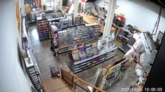 View of an art supply store from a security camera. Aisles of shelving and store displays are visible, a sculpture of an astronaut is hanging from the ceiling near the foreground.