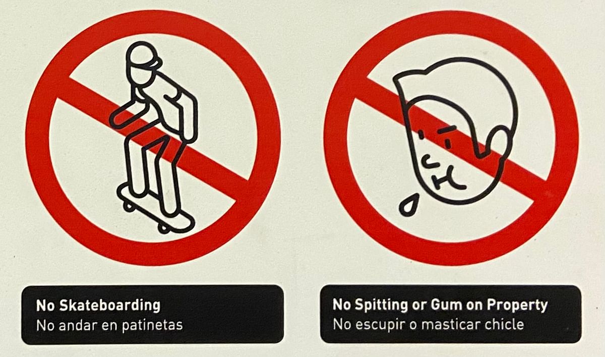 Two cartoons, one for “No skateboarding” which shows a male in a baseball cap skateboarding with a red circle-and-slashed line over it, and one for “No Spitting or Gum on Property” with a man spitting and another circle-and-slash overlay.